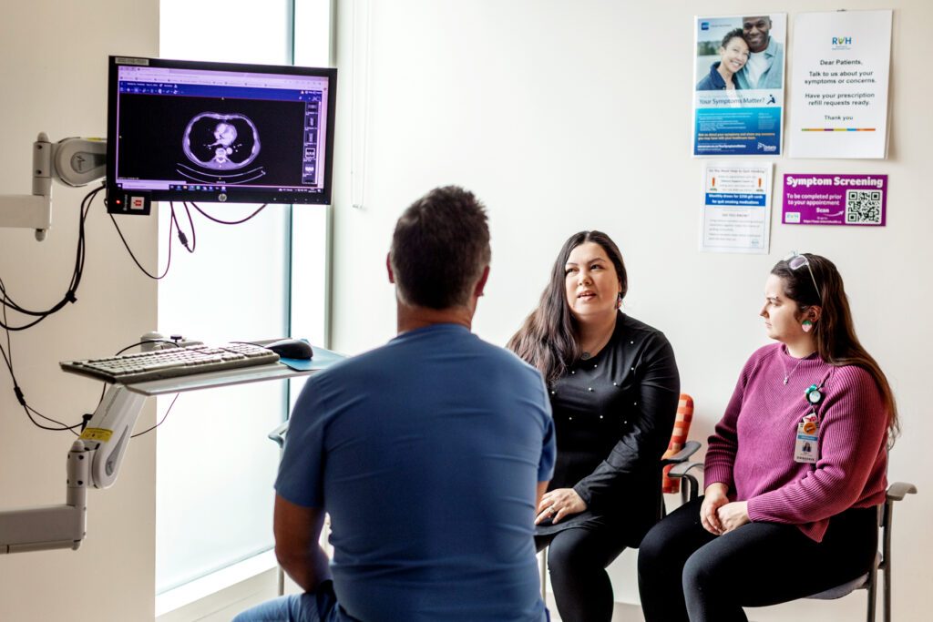 Two women with long, brown hair sit in chairs while one speaks to an ultrasound technician.